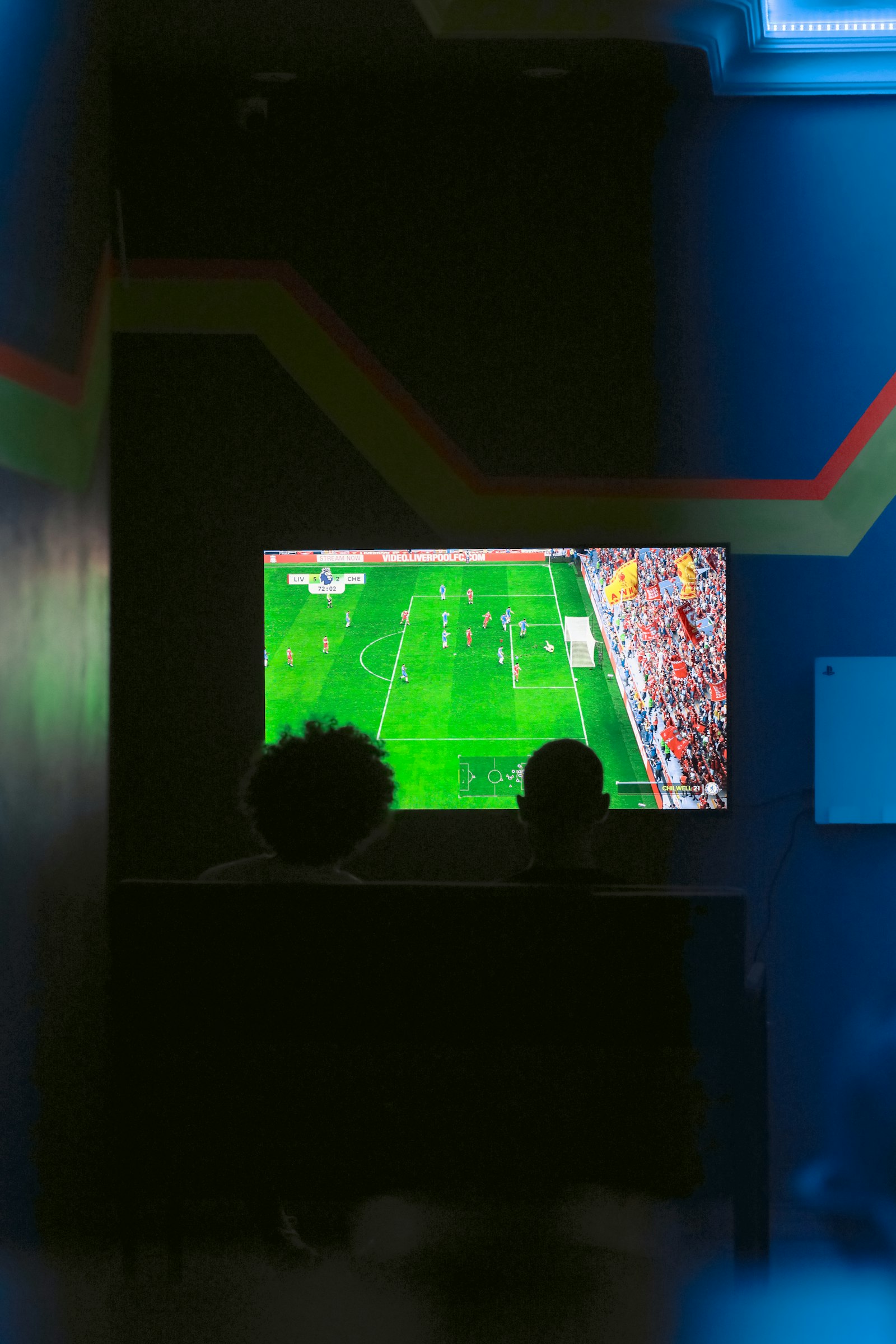 Dua orang nonton pertandingan bola di televisi, ilustrasi live streaming bola tanpa buffering