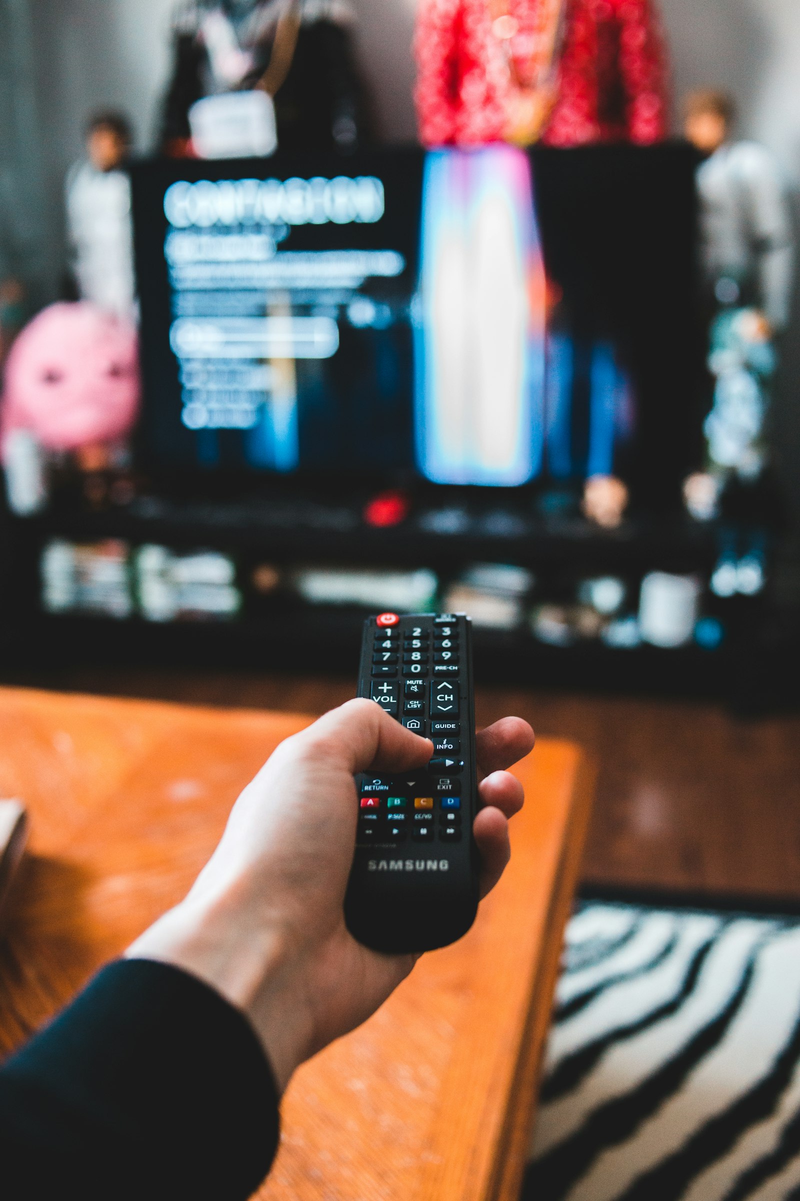 Tangan memegang remote mengarah ke TV yang sedang memutar video streaming
